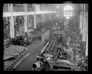 Four men standing in a factory making airplane parts including propellers