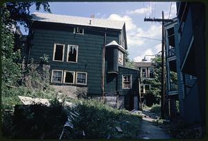 Side view of dark green house with broken windows, Roxbury, Boston