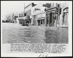 Muddy Missouri Invades Main Street in Pierre: - This wet view of Pierre's busiest street shows only boat traffic prevailed with more than four feet of water in most establishments and up to the eaves of the American Legion Cabin in the background. The boat shown is in front of The Daily Capital Journal and also houses the Associated Press Bureau here.