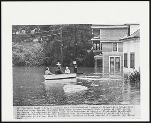 Rescue From Flood -- Oakland fireman Al Sigwart rows Mrs. Leonard Black and Zelma Trucano to safety from their flooded Oakland, Calif., homes at right yesterday. Others in background on porch, wait to be evacuated at height of flood which practically isolated the East Bay city. Note submerged auto in foreground. Height of water can be seen on telephone pole street sign in background. Location is Brook street.