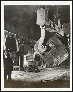 A Vital Wartime Metal - Manganese oxide nodules fill their wartime purpose in the production of open hearth steel. In one of the plants of the United States Steel corp., molten blast furnace iron is added to the open hearth furnace two or three hours after the scrap iron charge. It is transported in the transfer ladle shown here, carried by overhead crane from the storage mixer to the open hearth furnace. The molten iron is poured into the furnace with the aid of a portable trough inserted in the furnace door.
