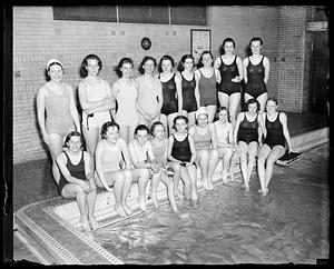 A group of women in swimsuits posing by the side of a pool