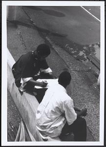 Junior Gabriel (on left) and another young man sitting and writing