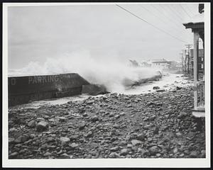 Storm-Whipped Waters of the Atlantic which lashed the entire Massachusetts coast yesterday are here seen roaring in over the sea wall at Scituate, littering Glade road with debris.