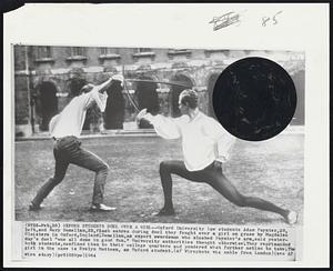 Oxford Students Duel over a Girl-- Oxford University law students Adam Poynter, 20, left, and Rory Donellan, 22, flash sabres during duel they fought over a girl on grass by Magdalen Cloisters in Oxford, England. Donellan, an expert swordsman who slashed Poynter's arm, said yesterday's duel "was all done in good fun." University authorities thought otherwise. They reprimanded both students, confined them to their college quarters and pondered what further action to take. The girl in the case is Evelyn Mottson, an Oxford student.