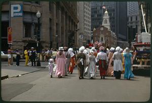 A group of people in colonial costume walking toward Old State House, Boston