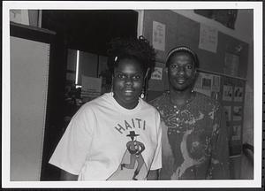 A young man and woman smiling in a hallway
