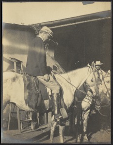 Man with cap on horse near stable