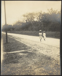Two woman walking down road near railroad tracks