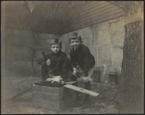 Two boys in barn area with hammers and wooden box