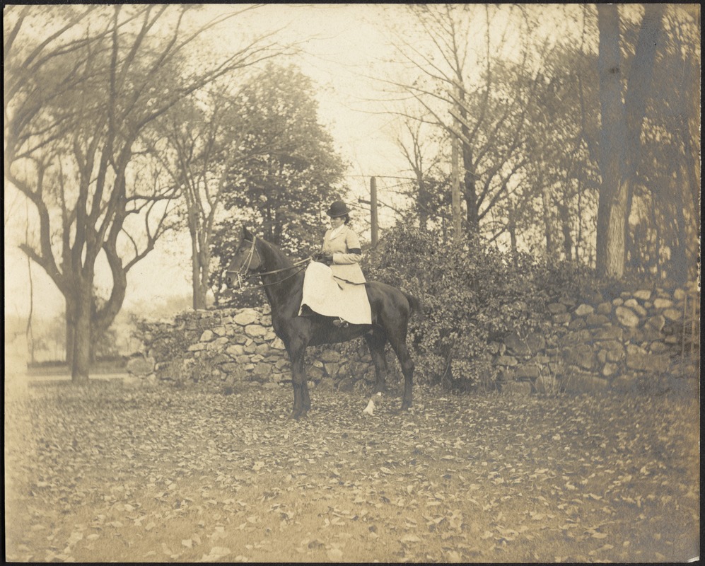 Gertrude Stevens Kunhardt on horseback in front of stone wall, Ashdale Farm.