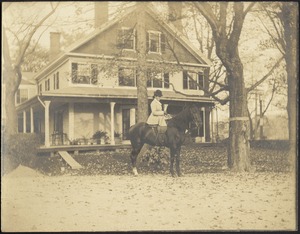 Gertrude Stevens Kunhardt sitting sidesaddle on horse in front of main house at Ashdale Farm