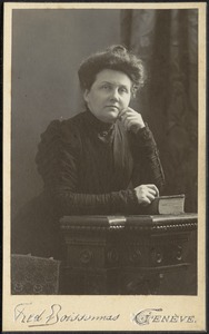 Georgia Lydia Stevens in dark dress seated at table with book