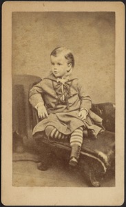 Young boy with striped stockings seated on chair