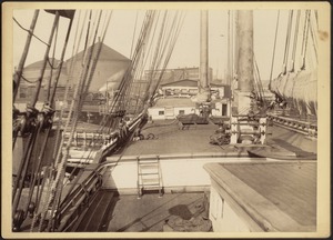 Deck of wooden sailing vessel; shipyard, roundhouse and steam engine in background; "Austin E. Welling Coal Co." sign visible