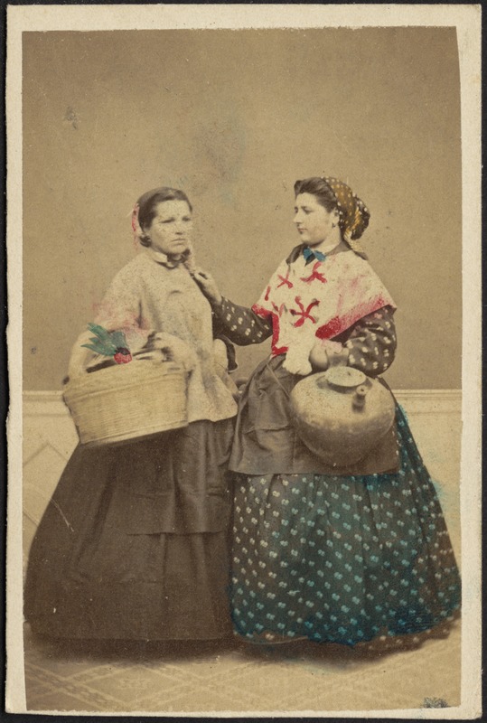 Studio portrait of two women in traditional dress carrying basket and