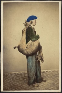 Studio portrait of young man in beret with dead deer slung over shoulder.
