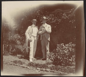 Two well-dressed gentlemen standing in garden