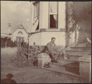 Adelbert S. Hay sitting on steps with small dog in front of house
