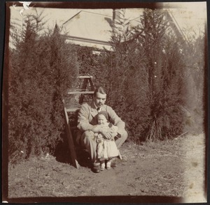 Consul Adelbert S. Hay sitting on step ladder holding small child