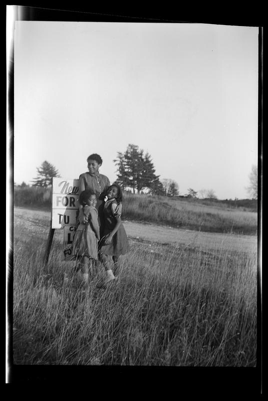 Yvonne and two girls pose in front of a sign