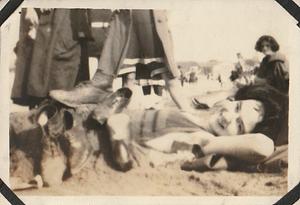 "Trix" lying on sand at a beach covered in shoes