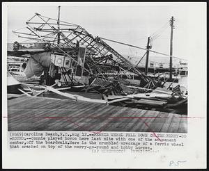 Ferris Wheel Fell Down on the Merry-Go-Round. -- Connie played hovoc here last nite with one of the amusement center, off the boardwalk. Here is the crumbled wreckage of a ferris wheel that crashed on top of the merry-go-round and hobby horses.