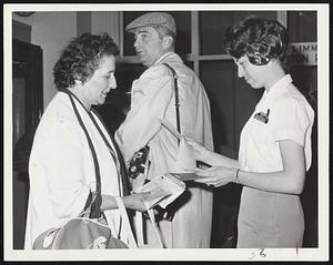 Greetings To America come from Miss Sisson of Winthrop, one of two port receptionists Boston Airport. Miss Sisson is checking passport and other documents for Mrs. Jacob Abers of San Francisco.