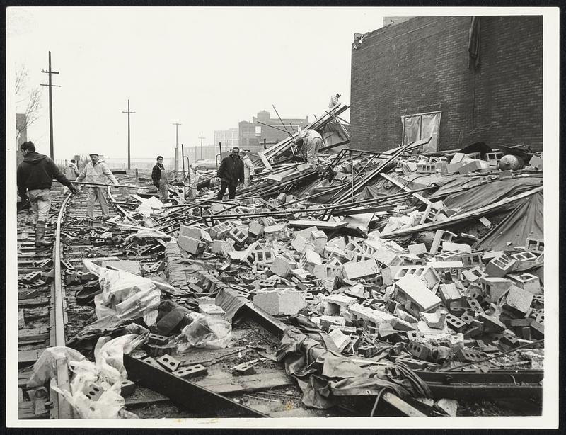 Workmen pick through debris of firehouse at Sullivan Square, Charlestown, that was under construction. Part of building was blown over storm that swept area.