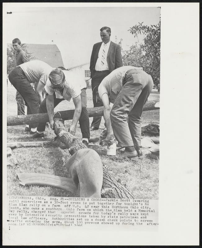 Building a Cross--Parkie Scott (wearing suit) supervises as a 30-foot cross is put together for tonight’s Ku Klux Klan rally on a farm off U.S. 42 near this Northern Ohio city. Scott, who owns a southern Ohio farm on which the Klan held a Memorial Day rally, charged that expected crowds for today’s rally were kept away by intensive security precautions taken by state patrolmen and local law officers. Authorities set up a dozen check points to screen traffic entering the area. About 100 persons showed up during the afternoon.