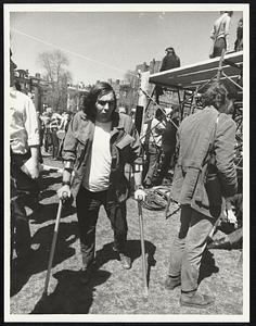 Unidentified Army veteran walks with aid of crutches at anti-war rally on Common.