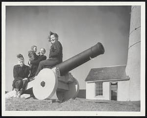 Fog Cannon which bears a 1700 date serves as a perch for, left to right, Mrs. Phyllis Davis of Portland, Me., Mrs. S Ray Beard of Tampa, Fla., and son, S. Ray Benway of Newport, R. I.