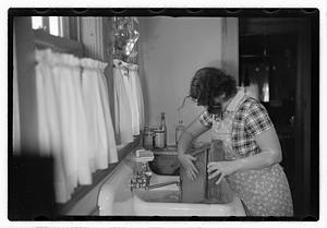 A woman doing laundry at a sink with a washboard