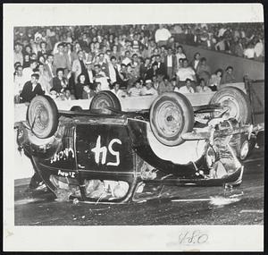 Crack-Up in Stock Car Race-Bud Richardson, whose helmeted head is visible through door window, awaits rescue after his auto skidded on a turn, bounced off the south wall and overturned during stock car race at Soldier Field in Chicago. Richardson suffered only minor cuts and bruises.