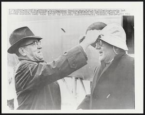 James Nealis, Mgr. P.T. & T. (L) adjust rain hat of California Gov. Edmund G. (Pat) Brown as he arrived in driving sleet at Arcata Airport near here 12/28 to inspect flood-ravaged Redwood Empire.