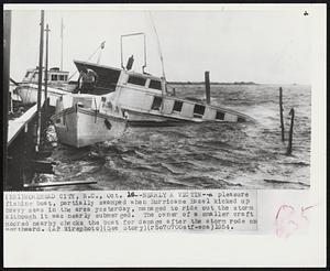 Nearly a Victim--A pleasure fishing boat, partially swamped when Hurricane Hazel kicked up heavy seas in the area yesterday, managed to ride out the storm although it was nearly submerged. The owner of a smaller craft moored nearby checks the boat for damage after the storm rode on northward.