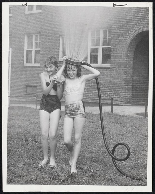 Coolest Crown in Town - Joanne Bower, 12, and Joyce Mangan, 12, left to right, of Old Colony Avenue, South Boston, share a lawn sprinkler to dodge heat.