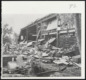 The business district of Papillion, a village at the southwest edge of Omaha, was among areas hardest hit. New cars (right) lie buried in piles of debris in garage. Wall collapsed under pressure of surging flood waters.