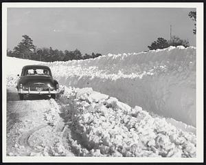 Wall Of Snow thrown up by huge rotary plow looms above a passing car at the junction of Route 6 and 132 on Cape Cod. Late last night the Cape area was still busy with the task of clearing the heavy fall.