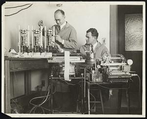 Showing how the new accounting device for department stores is operated. It does the work of a hundred or more clerks. Left to right, Prof. L. F. Woodruff of Technology and Edward Regal, its inventors.