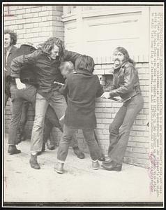 Demonstrator (L) has his arm around officer's neck, and uses his other hand to pummel the policeman, as another demonstrator uses the officer's own nightstick to hit him. Youth with back to camera is trying to jab officer in abdomen with stick to which Viet Cong flag is fastened.