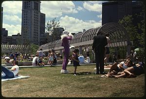 People sitting on grass, Christopher Columbus Park, Custom House Tower in background, a man dressed as a clown in foreground