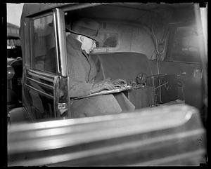 A man seated in the back of an automobile working unidentified equipment