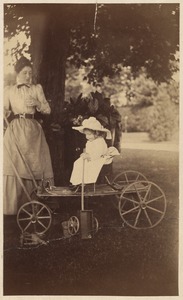 Portrait of a child in a wagon with a woman nearby