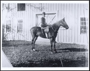 Miss Kate Cary: on horseback in front of barn door