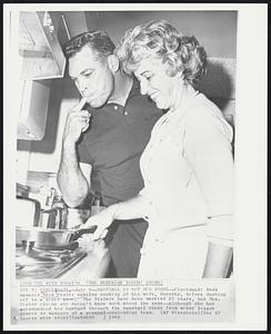 Baseball is Not Her Forte--Cincinnati Reds manager Dick Sisler samples cooking of his wife, Dorothy, before dashing off to a night game. The Sislers have been married 23 years, but Mrs. Sisler claims she doesn't know much about the game--although she has accompanied her husband through the baseball ranks from minor league player to manager of a pennant-contending team.