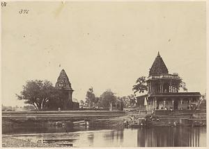 View of two unidentified temples next to tank or river