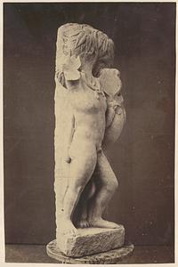 View of damaged sculpture of person and bird-like creature, on stool indoors, side view