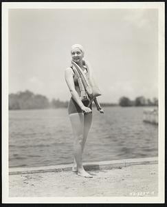 Although she outgrew waterwings a long time ago, comely Elaine Evorsole, Akron, Ohio, speed swimmer, tries on a life vest of a type used by aviators, to see how it fits. Manufactured for the U. S. Army Air Corps by The Firestone Tire & Rubber Company, the vest can be worn deflated without interfering with the movements of the wearer. Pulling a cord at the bottom of the vest punctures a carbon dioxide cartridge, fully inflating it in less than three seconds. The vest is so constructed that, should the wearer be unconscious or wounded, it automatically holds his face above water with no effort on his part.