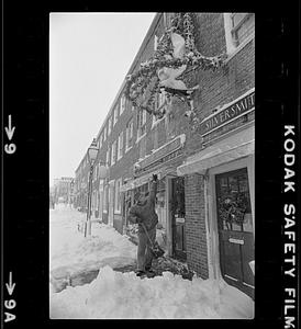 Shoveling snow in front of silversmith shop